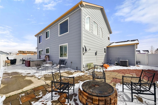 snow covered house featuring a patio, a hot tub, central AC, a fenced backyard, and a fire pit