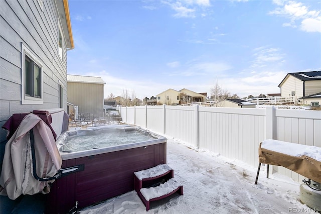 snowy yard with a residential view, a fenced backyard, and a hot tub