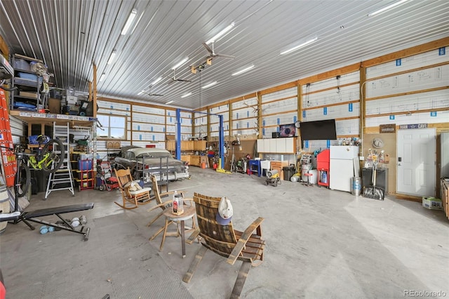 garage with a workshop area, metal wall, and freestanding refrigerator