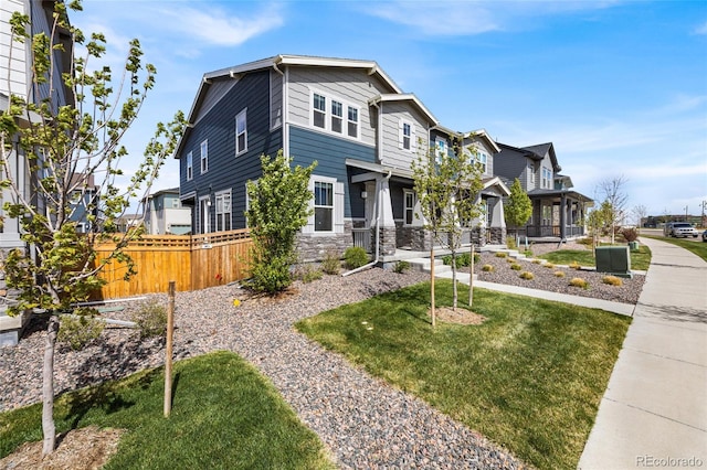 view of front of house with stone siding, a front lawn, and fence