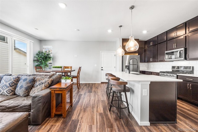 kitchen with appliances with stainless steel finishes, a breakfast bar, open floor plan, and light countertops