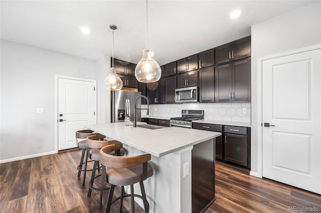 kitchen with tasteful backsplash, appliances with stainless steel finishes, dark wood-style flooring, and a sink