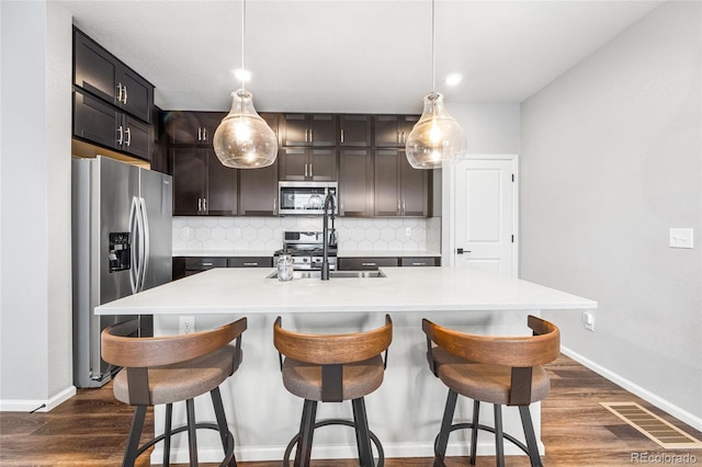 kitchen with appliances with stainless steel finishes, visible vents, a sink, and tasteful backsplash