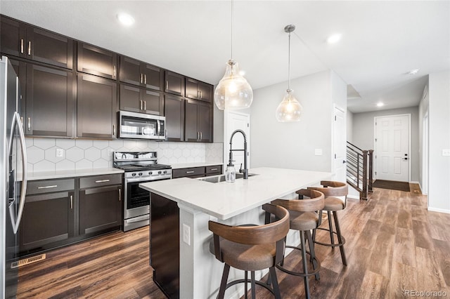 kitchen with stainless steel appliances, tasteful backsplash, dark wood-style flooring, and a sink