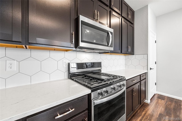 kitchen with light stone counters, dark wood finished floors, stainless steel appliances, tasteful backsplash, and baseboards