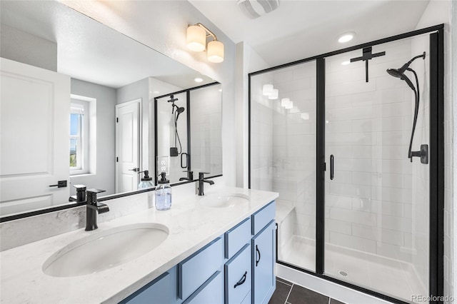 bathroom with a stall shower, a sink, and visible vents