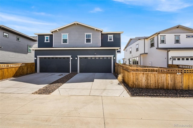 traditional home with fence, driveway, and an attached garage