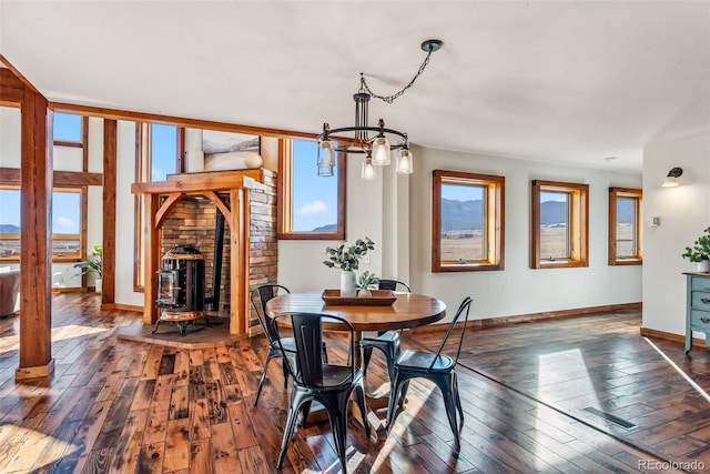 dining room with baseboards, dark wood-style flooring, and a wood stove