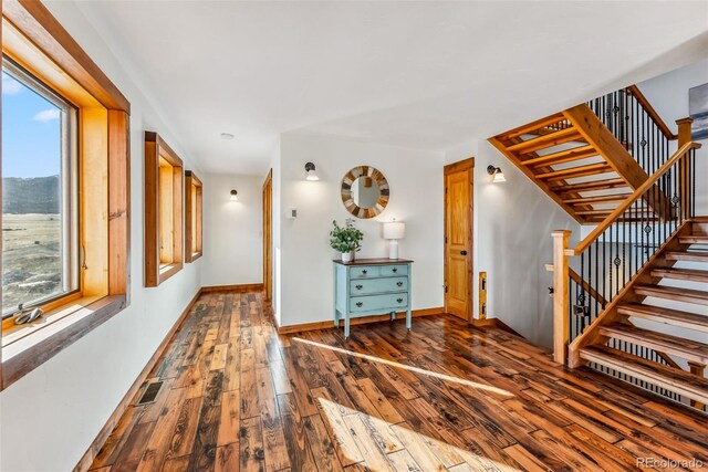 hall with hardwood / wood-style flooring, baseboards, visible vents, and stairway