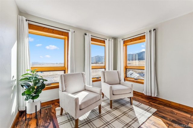 sitting room with wood finished floors, visible vents, and baseboards