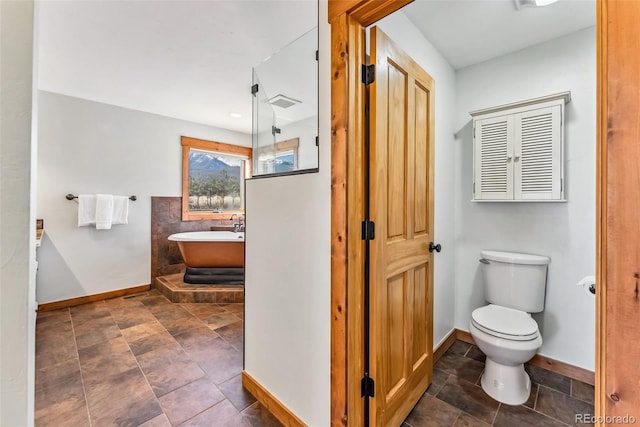 full bath featuring a soaking tub, toilet, and baseboards