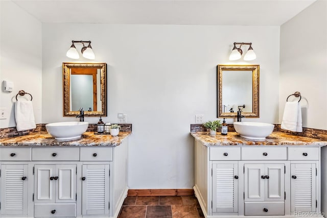 full bath with two vanities, baseboards, and a sink