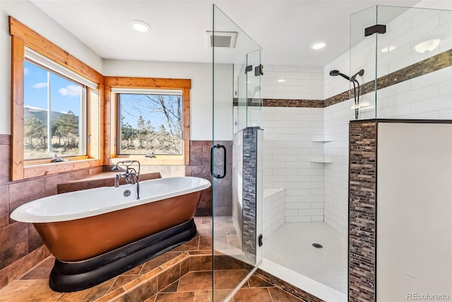 full bath with tile walls, tile patterned floors, a freestanding tub, and a stall shower