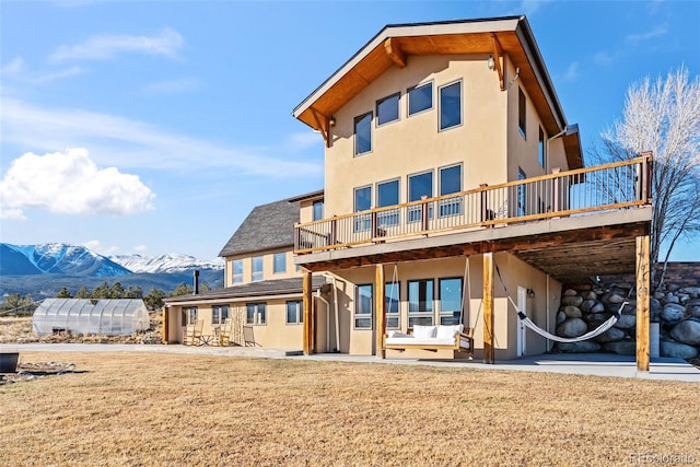 back of house featuring an exterior structure, a deck with mountain view, a patio area, an outdoor structure, and stucco siding