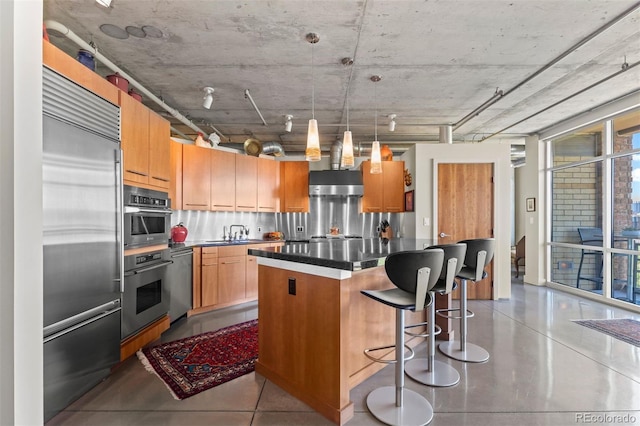 1610 Little Raven St Unit 502, Denver, CO 80202 - kitchen with appliances with stainless steel finishes, a center island, dark countertops, a breakfast bar, and pendant lighting