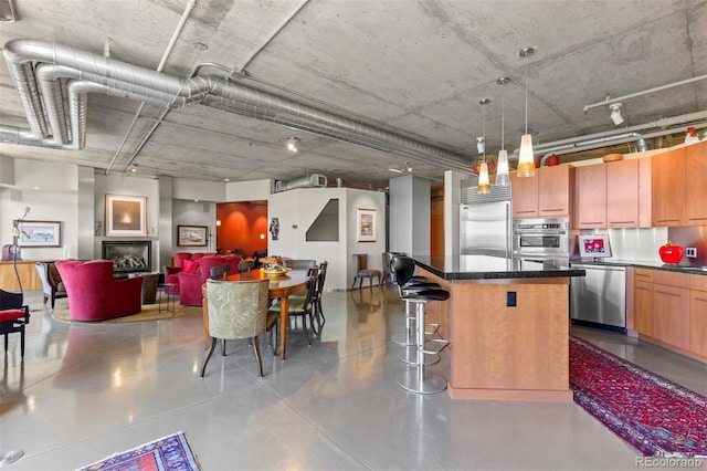 1610 Little Raven St Unit 502, Denver, CO 80202 - kitchen with appliances with stainless steel finishes, a center island, a breakfast bar, finished concrete flooring, and pendant lighting
