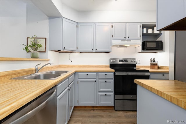 kitchen featuring dark wood finished floors, stainless steel appliances, under cabinet range hood, open shelves, and a sink