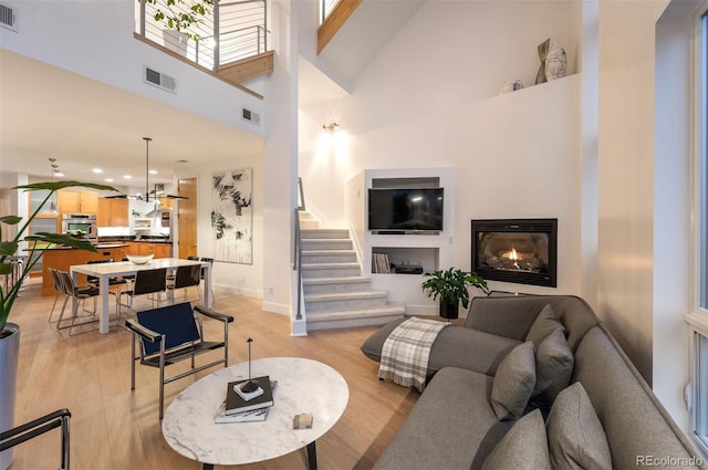 8071 E 29th Ave, Denver, CO 80238 - living area featuring stairs, light wood-type flooring, a towering ceiling, baseboards, and a glass covered fireplace
