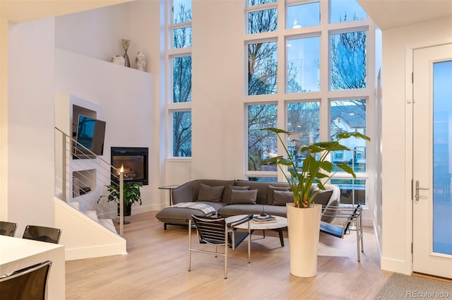 8071 E 29th Ave, Denver, CO 80238 - living area featuring a towering ceiling, baseboards, wood finished floors, stairway, and a glass covered fireplace