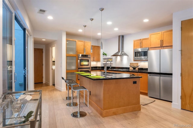 8071 E 29th Ave, Denver, CO 80238 - kitchen with stainless steel appliances, wall chimney exhaust hood, dark countertops, light wood-style flooring, and recessed lighting