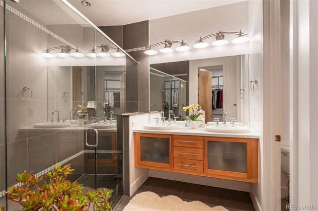 8071 E 29th Ave, Denver, CO 80238 - bathroom featuring double vanity, tile patterned floors, a shower stall, a walk in closet, and toilet