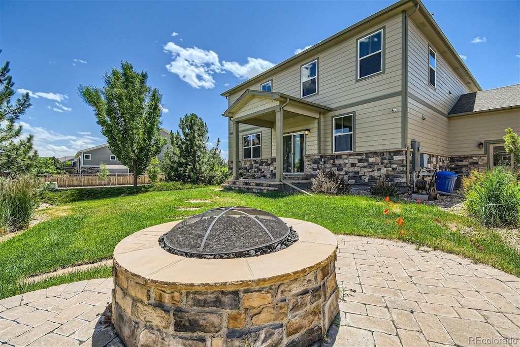 back of property featuring a lawn, a patio, and a fire pit