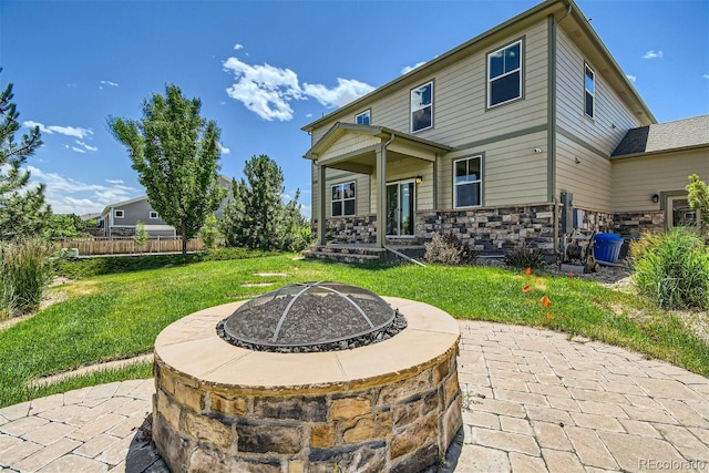 back of property featuring a lawn, a patio, and a fire pit