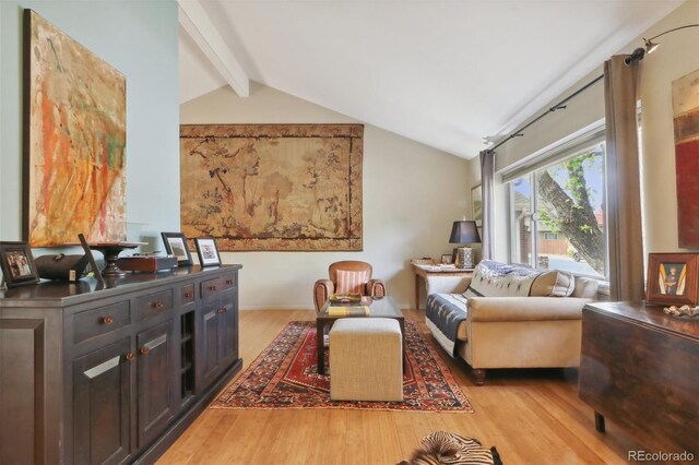 living area featuring light wood-type flooring and lofted ceiling with beams