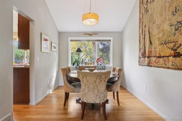 dining space with vaulted ceiling, light hardwood / wood-style flooring, and sink