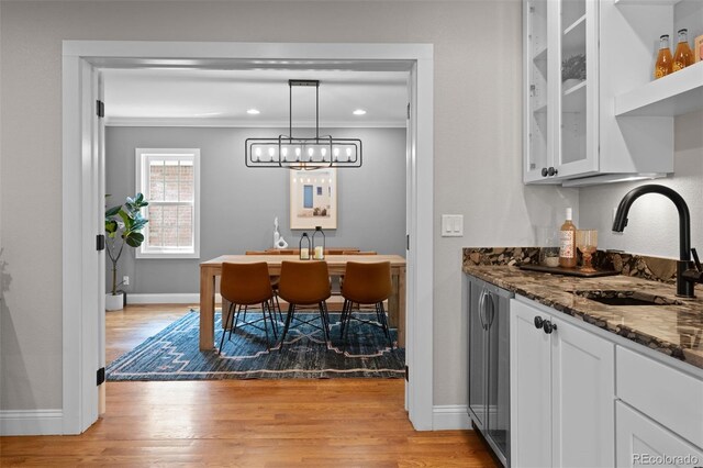 2485 S Fillmore St, Denver, CO 80210 - dining space featuring ornamental molding, light wood-style flooring, baseboards, recessed lighting, and bar with sink