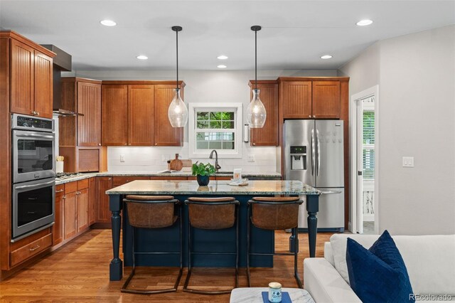2485 S Fillmore St, Denver, CO 80210 - kitchen featuring appliances with stainless steel finishes, backsplash, a breakfast bar area, light wood-style flooring, and plenty of natural light