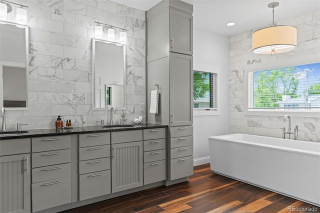 2485 S Fillmore St, Denver, CO 80210 - full bathroom featuring double vanity, a soaking tub, wood finished floors, decorative backsplash, and tile walls
