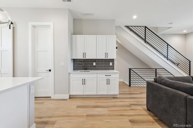 kitchen with sink, light wood-type flooring, and white cabinets