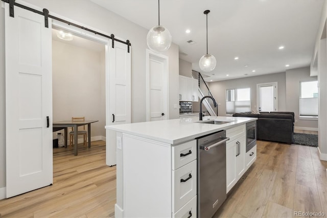 kitchen featuring white cabinetry, sink, a barn door, and a center island with sink