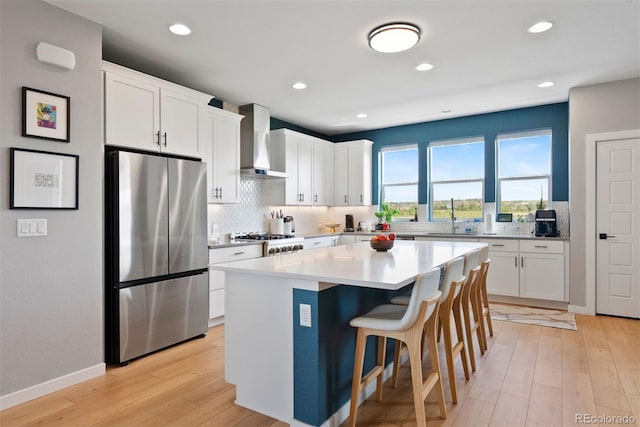 15020 Cast Pebble Cir, Parker, CO 80134 - kitchen featuring freestanding refrigerator, wall chimney range hood, decorative backsplash, white cabinetry, and recessed lighting