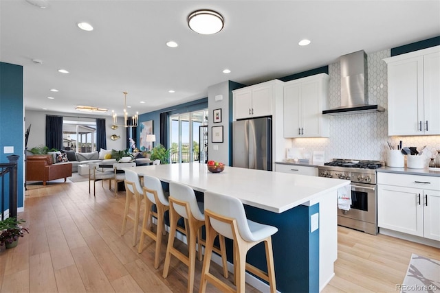 15020 Cast Pebble Cir, Parker, CO 80134 - kitchen with stainless steel appliances, wall chimney exhaust hood, a center island, backsplash, and light wood-style floors