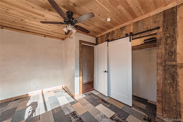 unfurnished bedroom featuring wood ceiling, a barn door, ceiling fan, and a closet