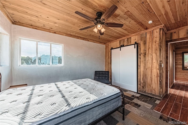 bedroom featuring wood ceiling, dark hardwood / wood-style flooring, wood walls, and a barn door