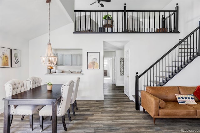 dining room featuring dark hardwood / wood-style floors, ceiling fan with notable chandelier, and a towering ceiling