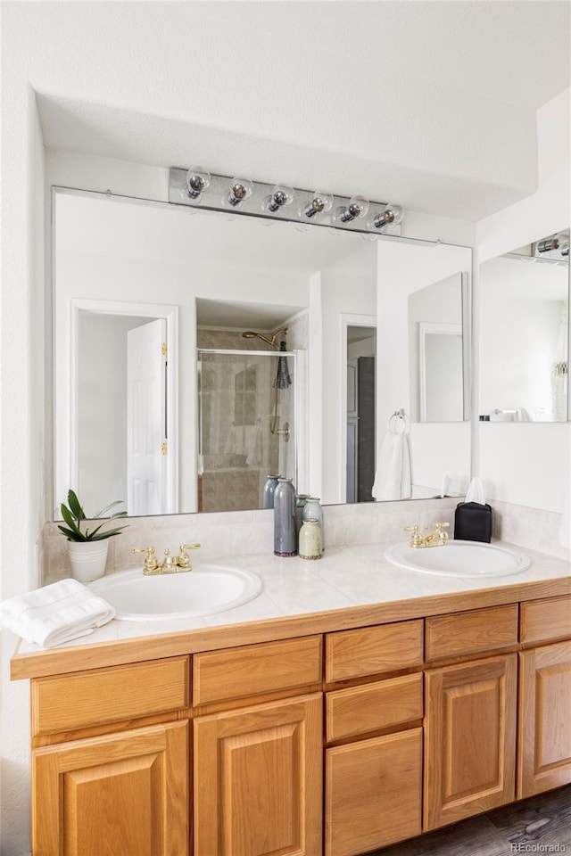 bathroom featuring a stall shower, a sink, and double vanity