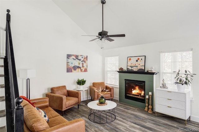 living room with ceiling fan, a fireplace, wood finished floors, baseboards, and vaulted ceiling