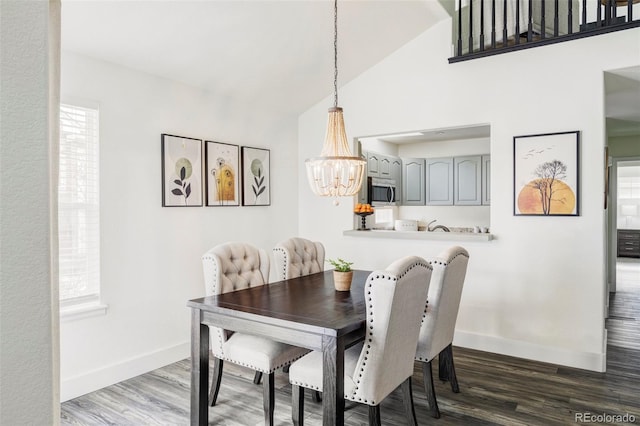 dining room with a chandelier, high vaulted ceiling, wood finished floors, and baseboards