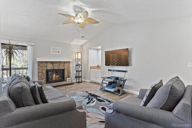 living area with wood finished floors, vaulted ceiling, a ceiling fan, baseboards, and a textured ceiling