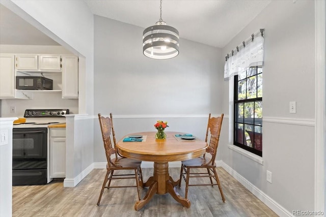 dining space with light wood-type flooring, a chandelier, baseboards, and lofted ceiling