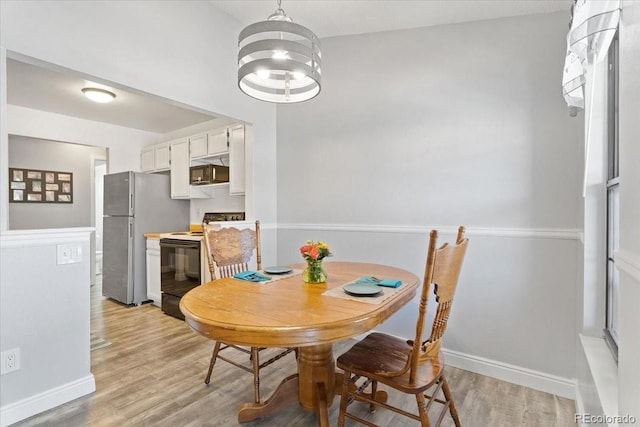 dining room with light wood-style flooring, baseboards, and a chandelier