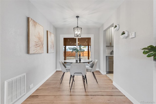 dining area featuring light wood-type flooring and a notable chandelier