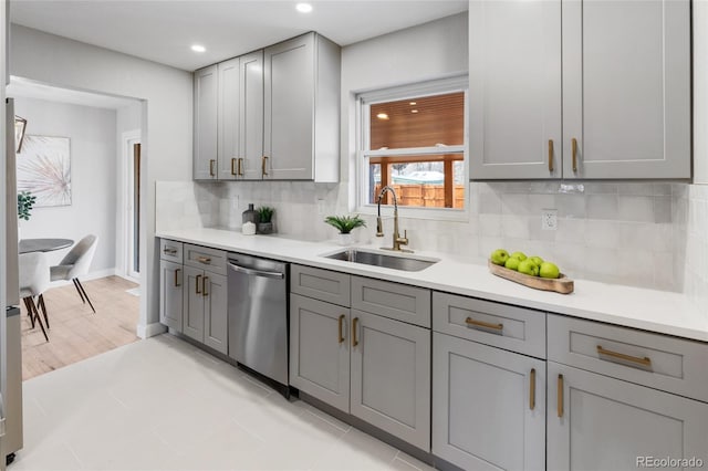 kitchen featuring dishwasher, gray cabinets, light tile patterned floors, sink, and tasteful backsplash