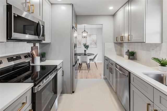 kitchen with stainless steel appliances, hanging light fixtures, tasteful backsplash, and gray cabinetry