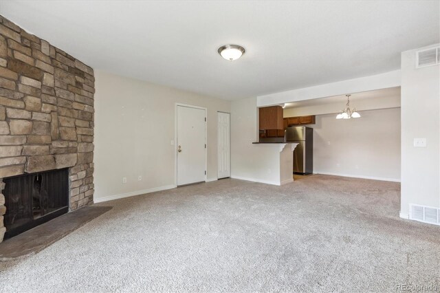 unfurnished living room featuring light colored carpet, a stone fireplace, and baseboards