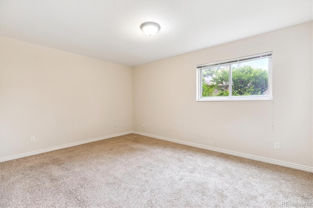 carpeted empty room featuring baseboards